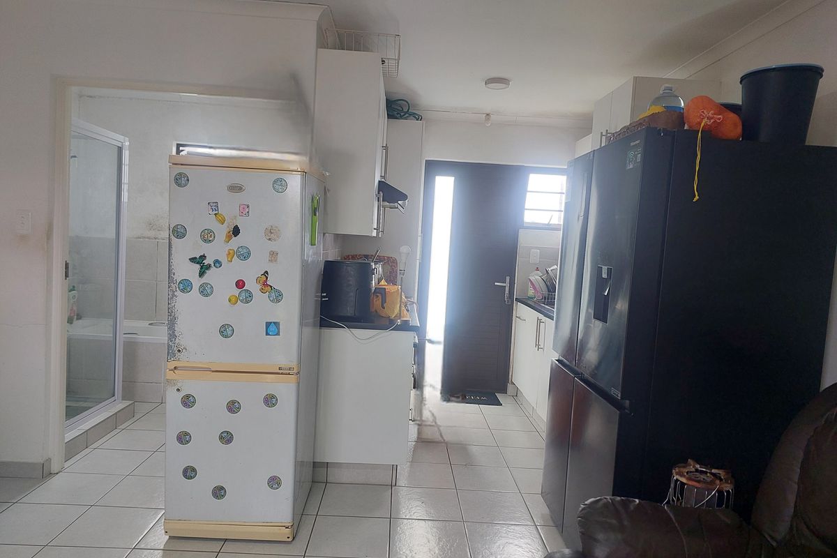 A functional kitchen area featuring tiled flooring and built-in cabinetry, with an adjacent bathroom entrance visible.
