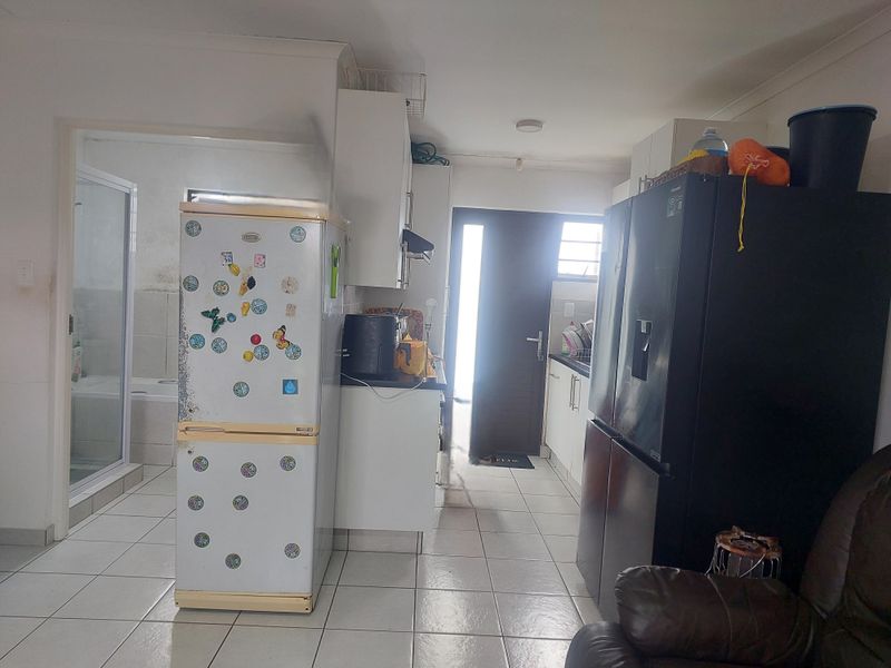 A functional kitchen area featuring tiled flooring and built-in cabinetry, with an adjacent bathroom entrance visible.