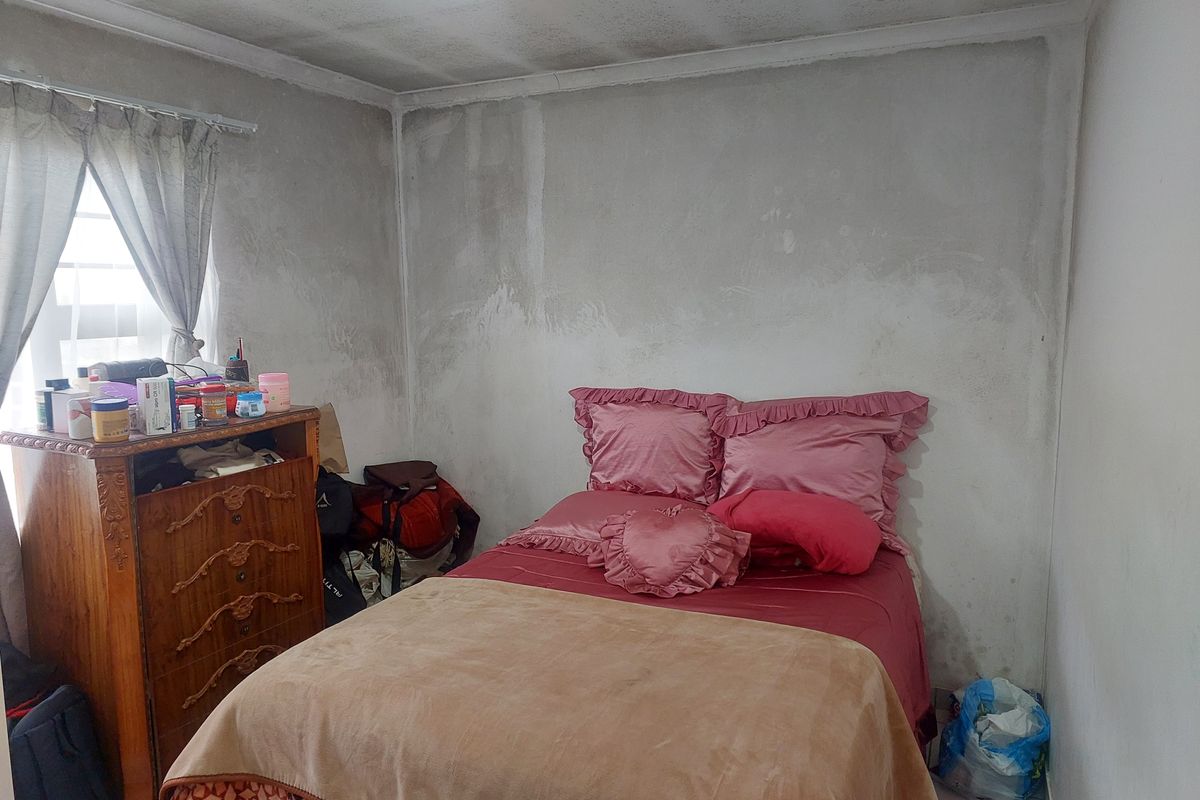 A bedroom featuring plain walls with visible signs of moisture damage and staining, requiring maintenance and cosmetic updates.