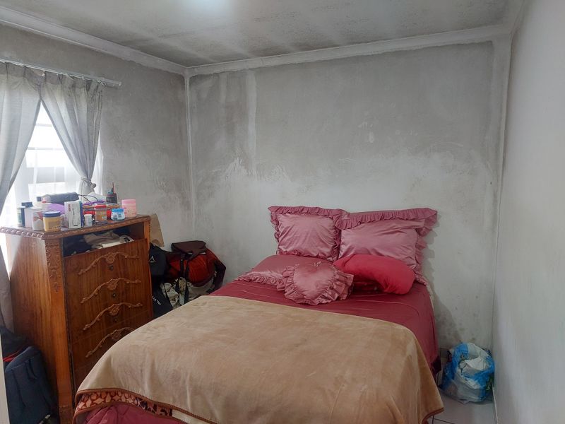 A bedroom featuring plain walls with visible signs of moisture damage and staining, requiring maintenance and cosmetic updates.