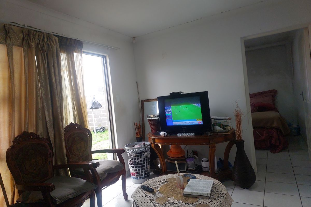A living room area featuring tiled flooring and a sliding glass door leading to the exterior, showing signs of wear and maintenance needs.