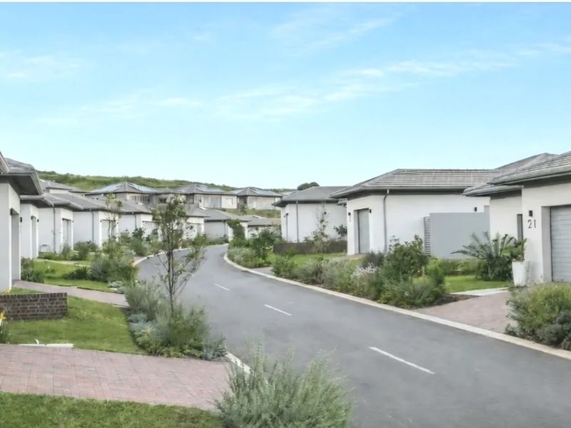 A view of a residential street within a modern estate, featuring well-maintained homes with paved driveways and landscaped gardens.
