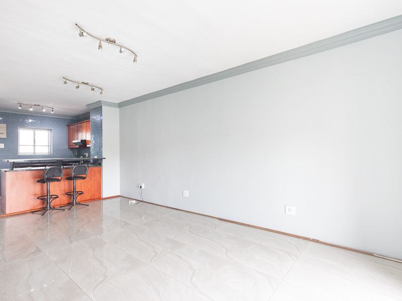Open plan living area featuring tiled floors, crown molding, and a breakfast bar connecting to a functional kitchen space.