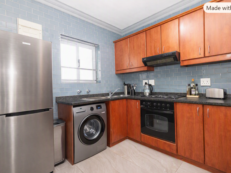 A functional kitchen featuring wooden cabinetry, granite countertops, subway tile backsplash, and integrated appliances including an oven, hob, and extractor fan.