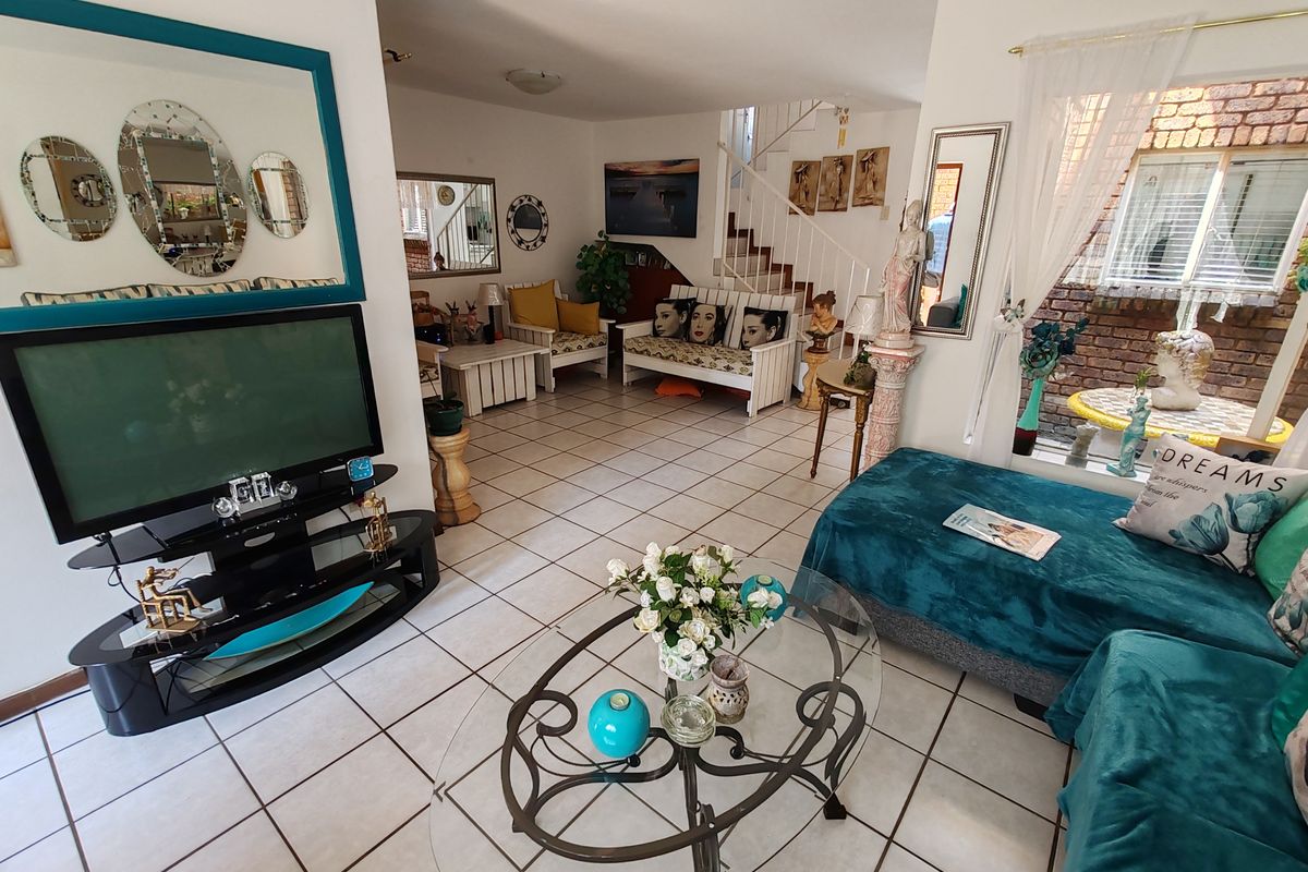 Spacious living area featuring ceramic floor tiles and an internal staircase, offering a functional layout with natural light from the side window.