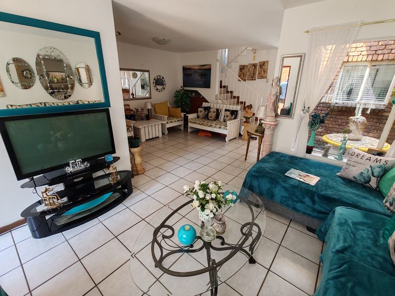 Spacious living area featuring ceramic floor tiles and an internal staircase, offering a functional layout with natural light from the side window.