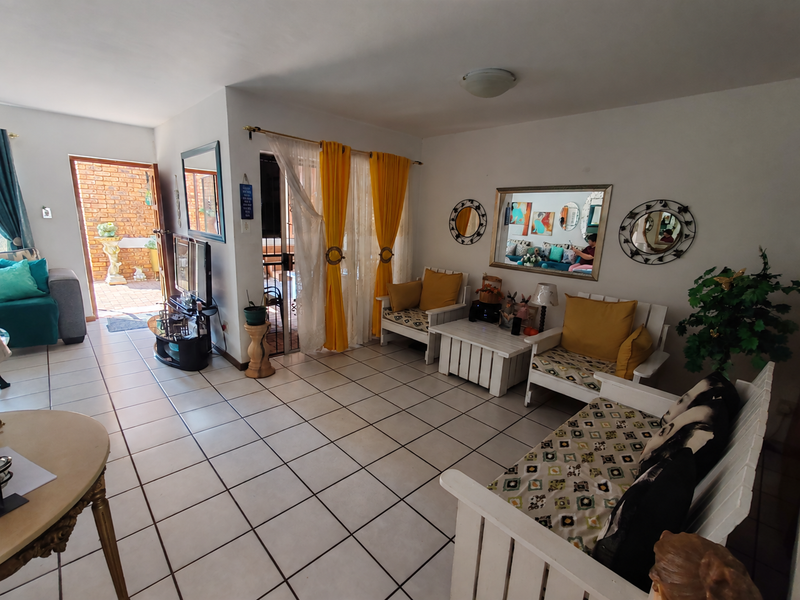 A bright living room featuring ceramic floor tiles and a sliding glass door providing direct access to an outdoor patio area.