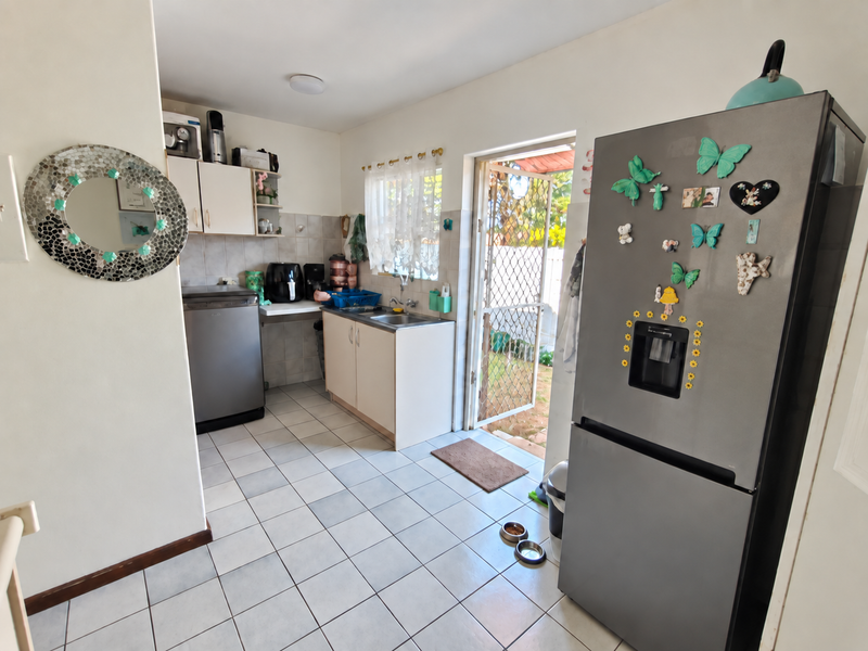 Functional kitchen area featuring tiled flooring, built-in cabinetry, and direct access to the rear exterior through a security gate.