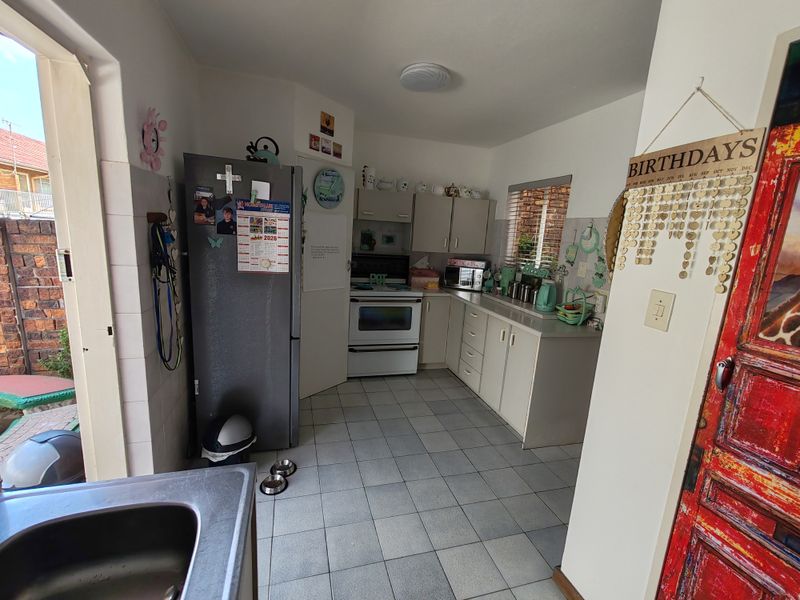 A functional kitchen featuring tiled flooring, built-in cabinetry, and a standard oven and hob setup, with direct access to an outdoor area.