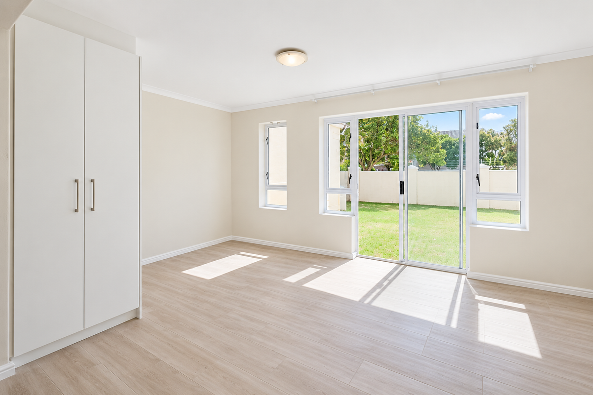 Bright and spacious bedroom featuring light laminate flooring, a built-in wardrobe, and sliding glass doors providing direct access to the rear garden.