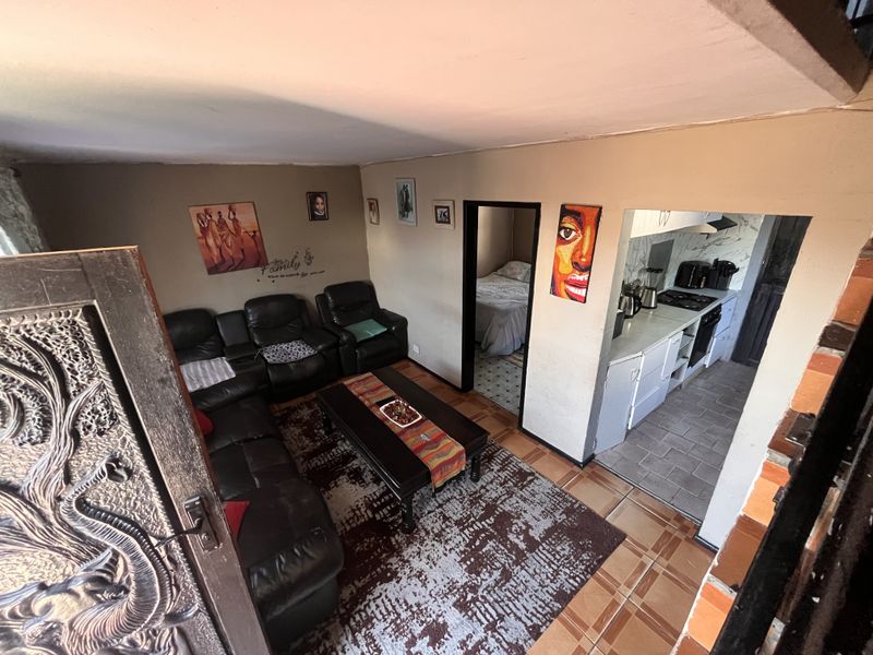 Open plan living area featuring a connected kitchen with built-in appliances and tiled flooring, providing a functional layout for daily living.