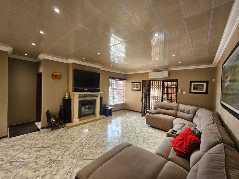 Spacious living room featuring tiled flooring, a built-in fireplace with mantelpiece, recessed lighting, and direct access to an outdoor area via security gates.