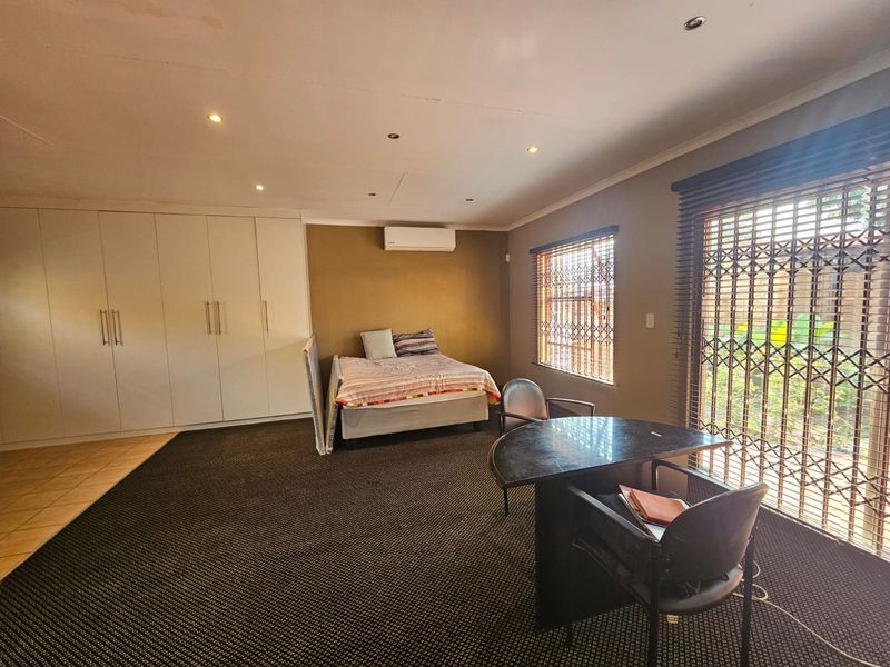 Spacious bedroom featuring extensive built-in cupboards, split-system air conditioning, recessed lighting, and secure window and door treatments.