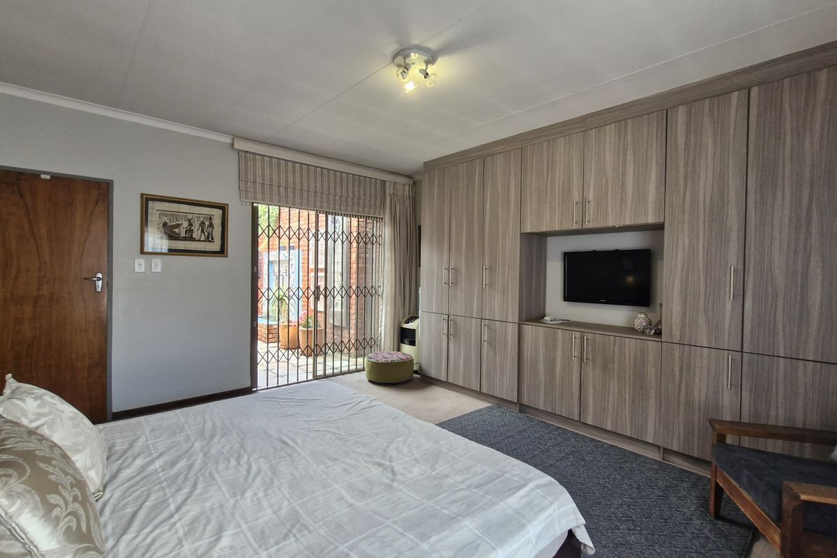 Spacious bedroom featuring extensive built-in cabinetry, neutral finishes, and a sliding glass door providing access to an outdoor area.