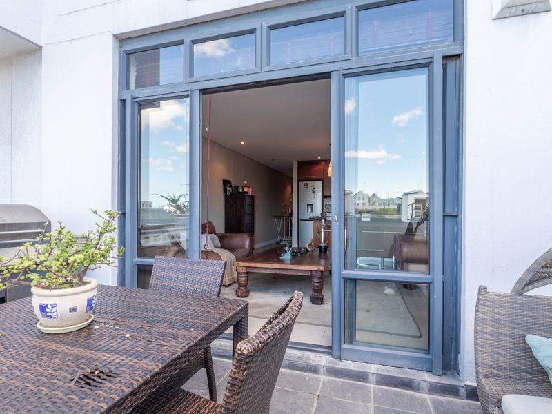 A covered patio area featuring tiled flooring, a built-in gas grill, and large sliding glass doors providing access to the interior living space.