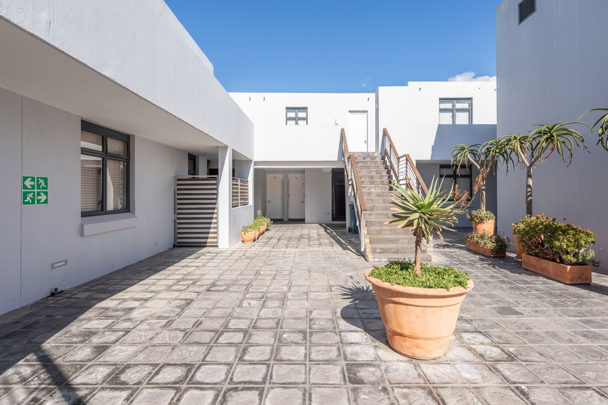 A well-maintained paved courtyard area featuring a central concrete staircase with metal handrails, providing access to upper-level apartment units.