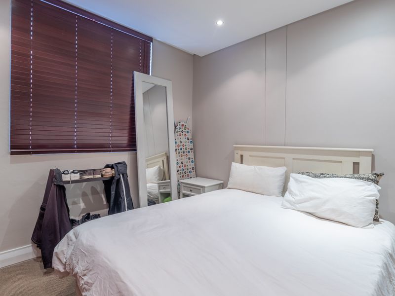 A well-maintained bedroom featuring neutral walls, recessed downlighting, carpeted flooring, and a built-in wardrobe with venetian blinds.