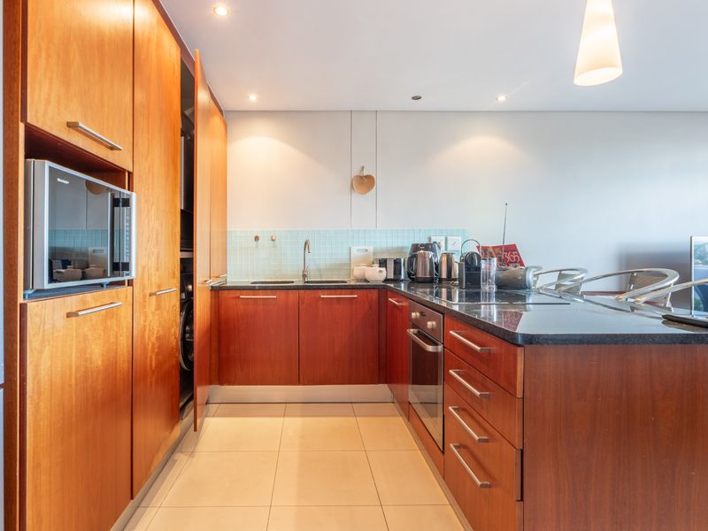 Modern kitchen featuring warm wood cabinetry, granite countertops, integrated appliances, and a tiled backsplash, offering a functional and well-maintained cooking space.