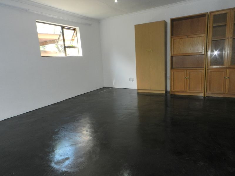 A bedroom featuring painted concrete flooring, built-in wooden cabinetry, and a casement window, offering a blank canvas for potential interior updates.