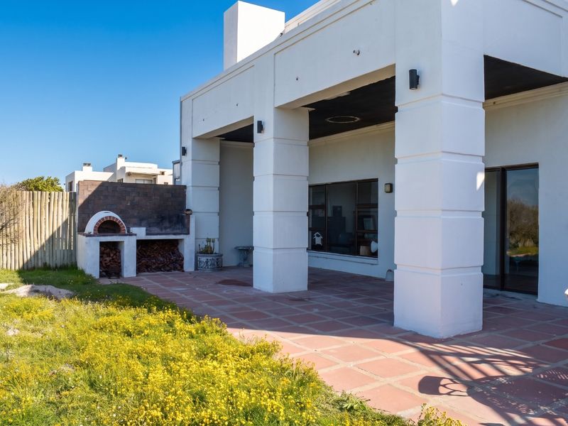Covered patio area featuring a built-in braai, tiled flooring, and large sliding doors providing seamless access to the garden.