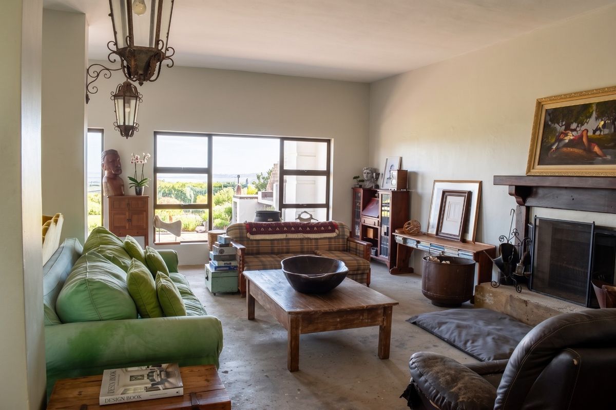 Spacious living room featuring a fireplace, large windows with natural light, and industrial-style concrete flooring, offering a versatile space for relaxation.