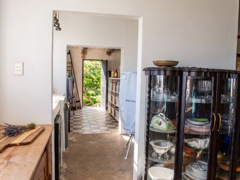 A functional scullery or utility area featuring tiled flooring and direct access to the rear garden, providing practical space for household tasks.