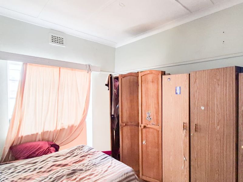 A bedroom featuring built-in wooden cupboards and standard ceiling finishes, requiring cosmetic updates to the wall surfaces.