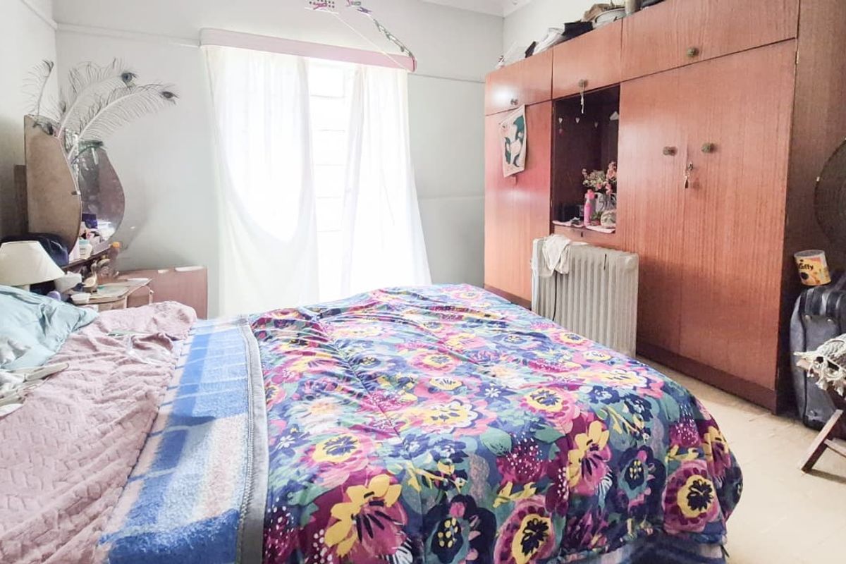 A bedroom featuring built-in wooden cupboards and natural light from the window.