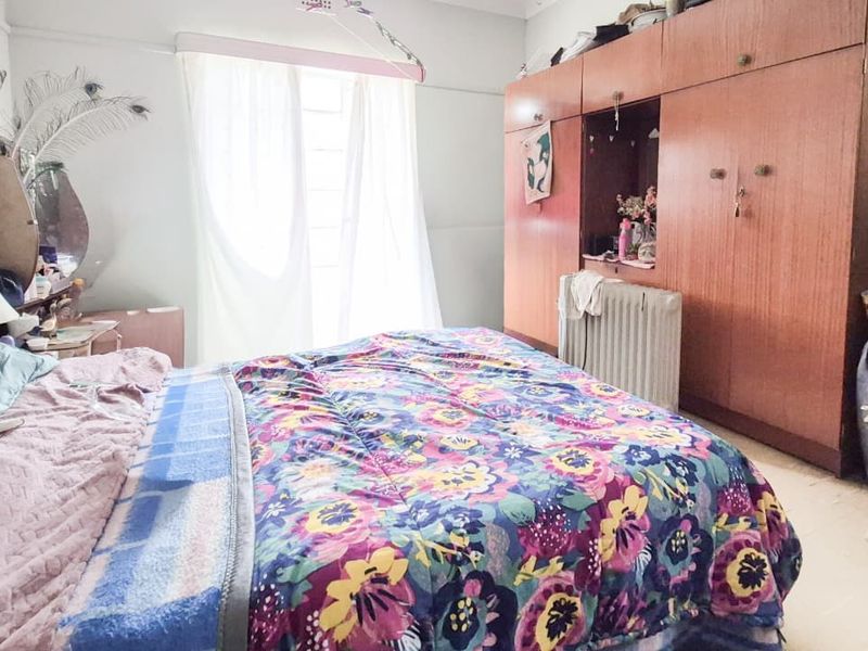A bedroom featuring built-in wooden cupboards and natural light from the window.