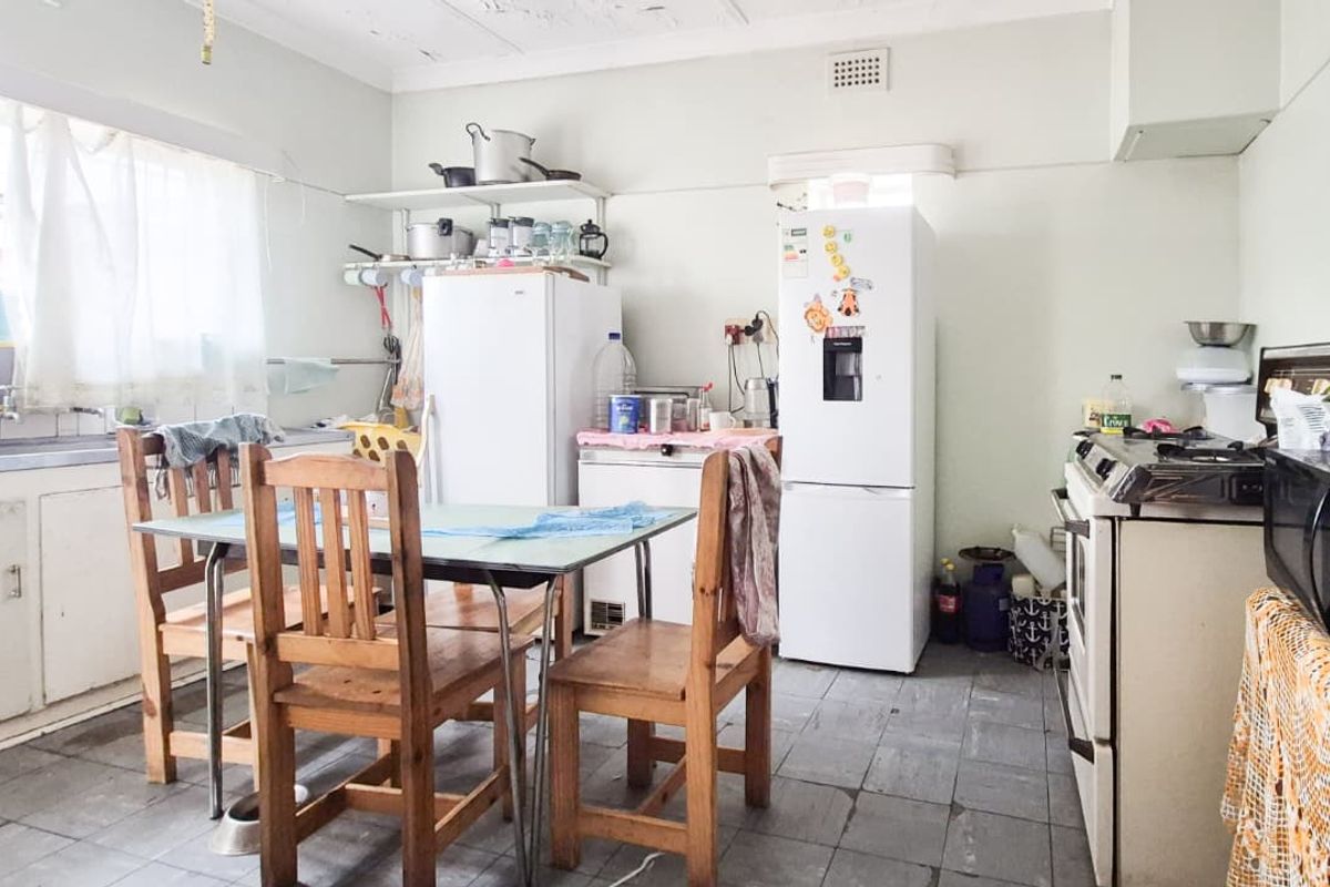 A functional kitchen space featuring original cabinetry, a stainless steel sink, and tiled flooring, offering significant potential for modernization and renovation.