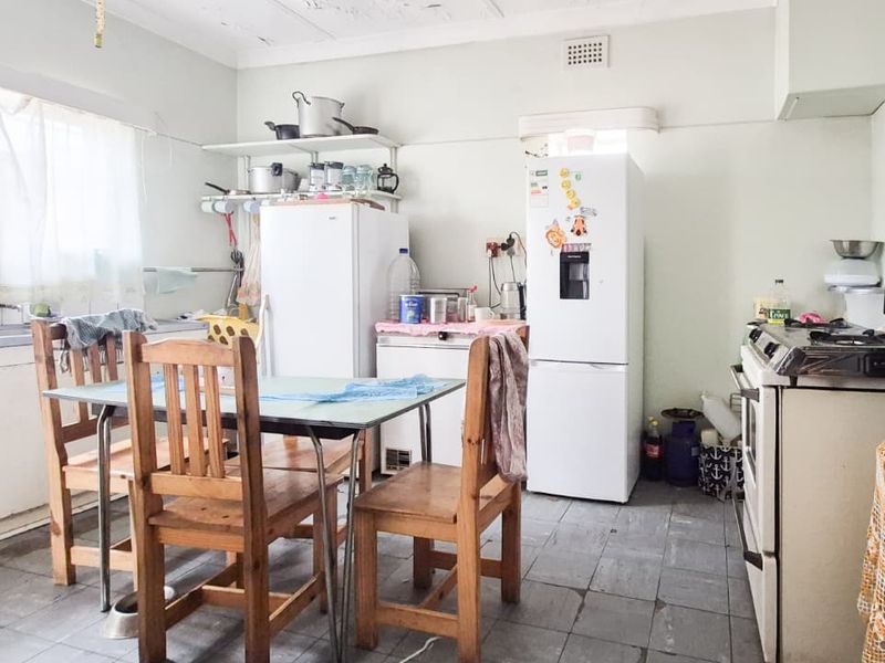 A functional kitchen space featuring original cabinetry, a stainless steel sink, and tiled flooring, offering significant potential for modernization and renovation.