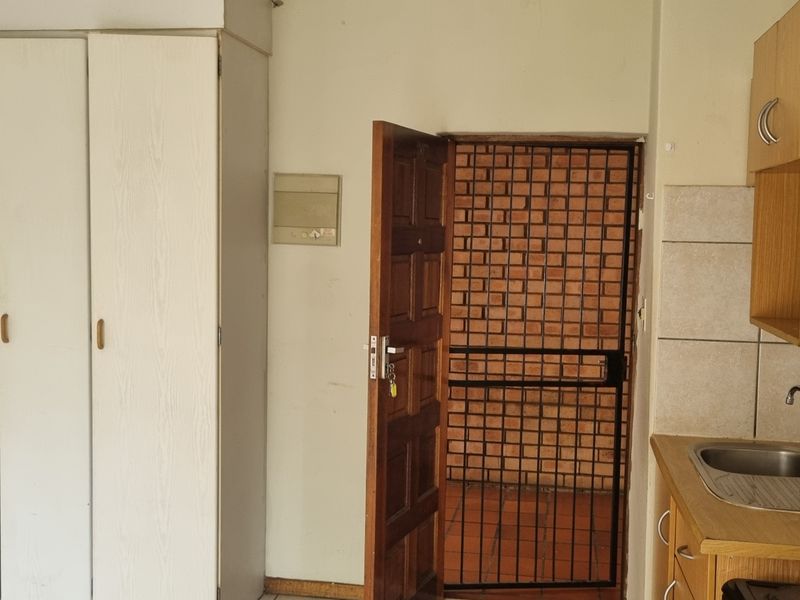 A compact kitchen area featuring built-in cabinetry, a stainless steel sink, and direct access to an exterior security gate.