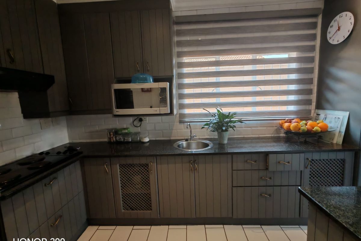 A well-maintained kitchen featuring dark grey cabinetry, granite countertops, subway tile backsplash, and integrated appliances, offering a functional and modern cooking space.