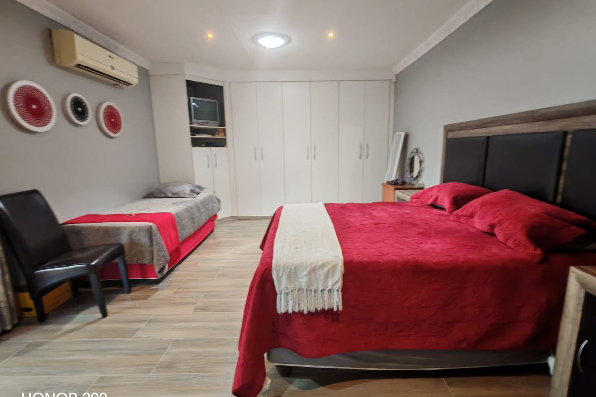 Spacious bedroom featuring built-in cupboards, tiled flooring, recessed lighting, and an integrated air conditioning unit.
