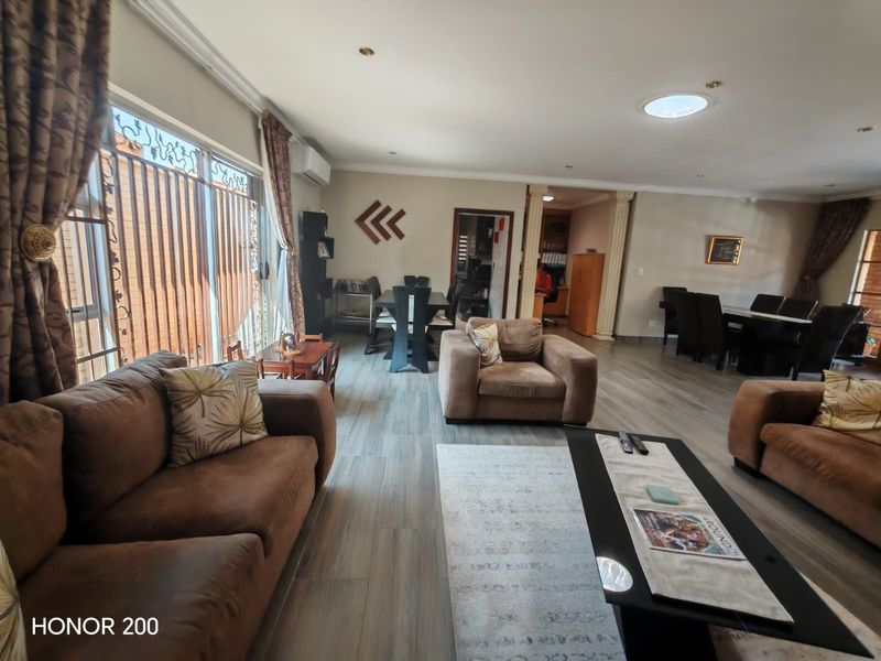 Spacious open-plan living and dining area featuring tiled flooring, recessed lighting, a skylight, and large sliding doors providing ample natural light.