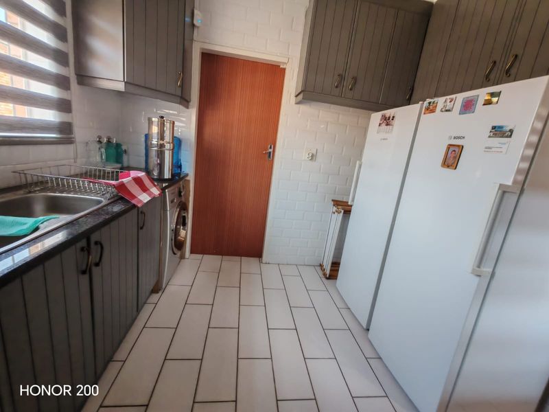 A functional scullery featuring built-in cabinetry, a stainless steel sink, subway tile backsplash, and tiled flooring, providing additional utility space.