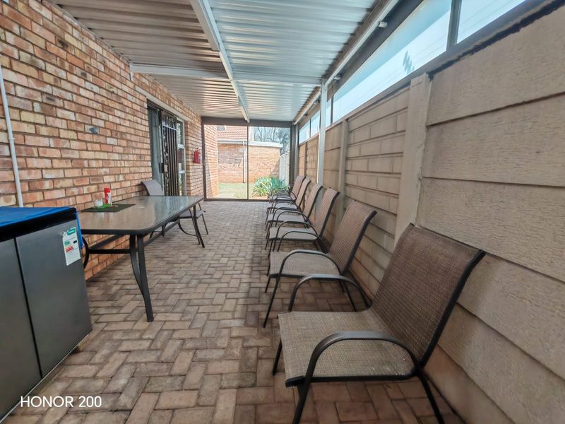 A covered outdoor patio area featuring brick and concrete wall finishes, paved flooring, and a corrugated metal roof structure.
