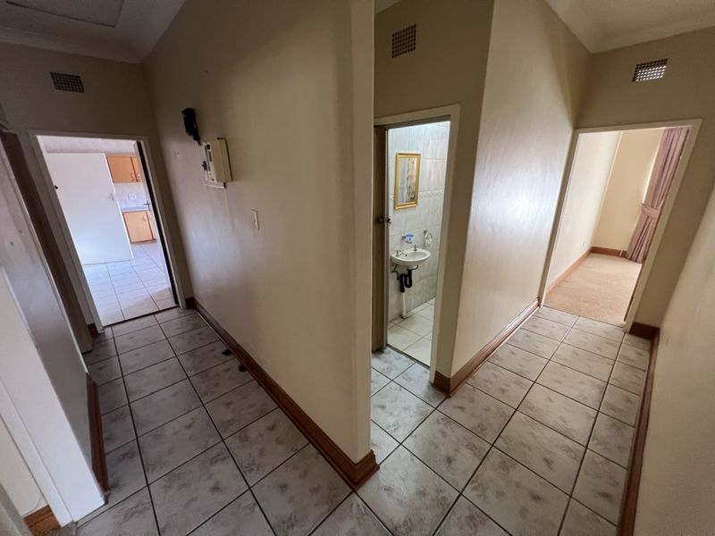 A central hallway featuring tiled flooring, providing access to multiple rooms including a bathroom and kitchen area.