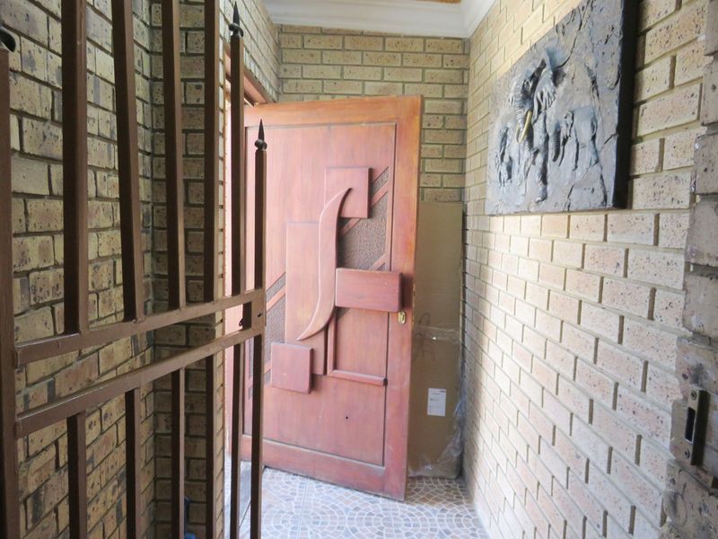 Entrance foyer featuring face-brick walls, tiled flooring, and a decorative solid wood front door with an integrated security gate.