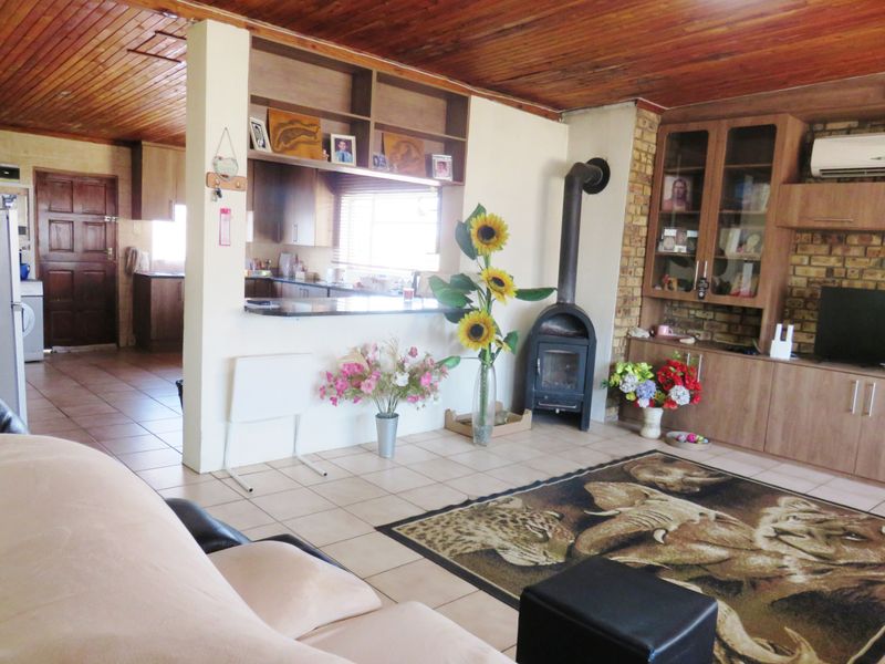 Open-plan living area featuring a wood-paneled ceiling, tiled floors, a cozy fireplace, and a breakfast bar connecting to the kitchen.