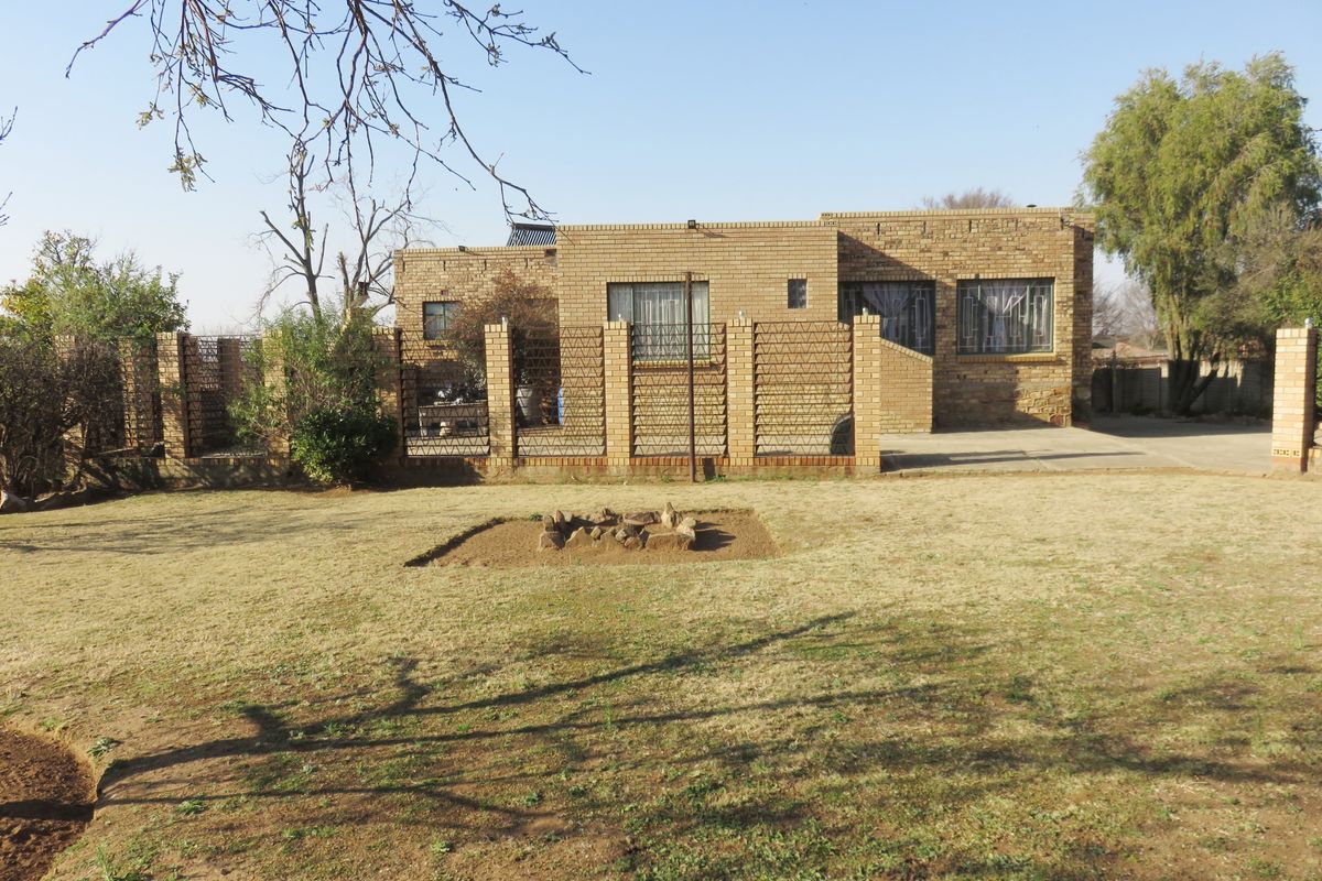 Rear view of a face brick house featuring a large garden, security bars on windows, and a solar water heating system.