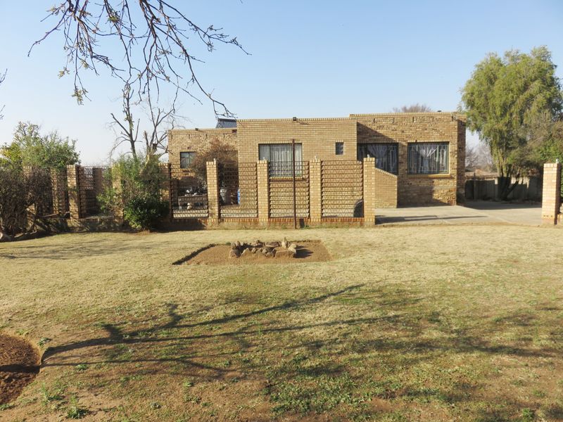 Rear view of a face brick house featuring a large garden, security bars on windows, and a solar water heating system.