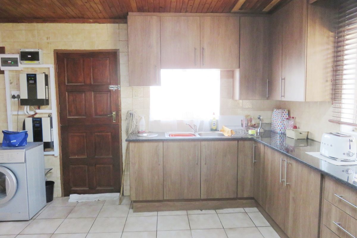 Functional kitchen featuring wood-look cabinetry, granite countertops, double basin sink, and tiled flooring, complemented by a timber-paneled ceiling.