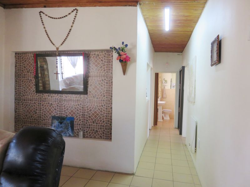 A hallway featuring tiled flooring and a timber ceiling, leading towards a bathroom area with a decorative tiled accent wall.