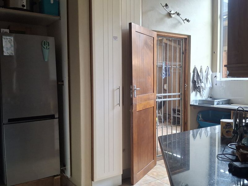 A functional kitchen featuring granite countertops, built-in cabinetry, and direct access to an outdoor utility area through a solid wood door.
