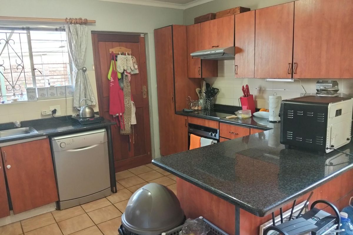 Functional kitchen featuring granite countertops, built-in wooden cabinetry, and tiled flooring, offering a practical layout with integrated cooking appliances.