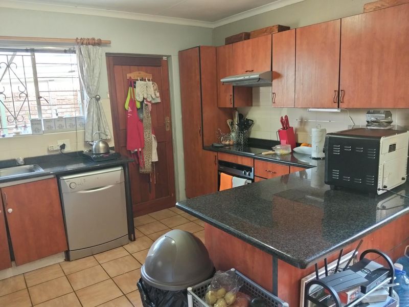 Functional kitchen featuring granite countertops, built-in wooden cabinetry, and tiled flooring, offering a practical layout with integrated cooking appliances.