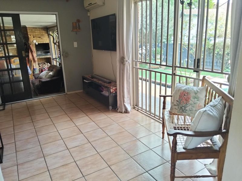 Living room featuring tiled flooring, air conditioning, and a sliding security gate leading to the garden, with an adjacent room containing a built-in fireplace.