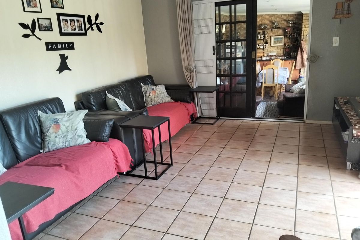A living room featuring tiled flooring and a sliding glass door leading to an adjacent dining area.