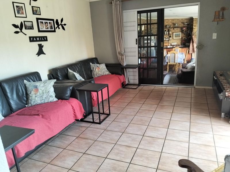 A living room featuring tiled flooring and a sliding glass door leading to an adjacent dining area.